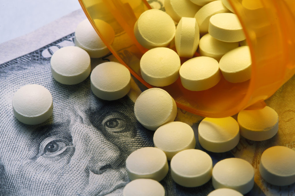 Pills Spill Out On To One Hundred Dollar Bill From Open Prescription Bottle