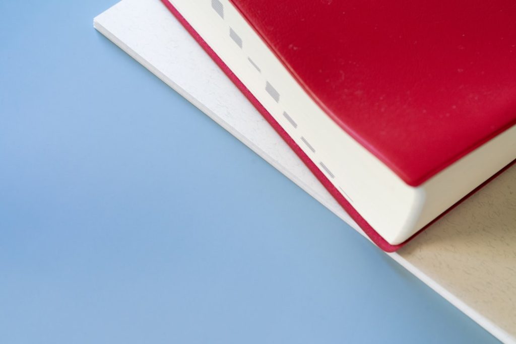 A red book sitting on top of a white book